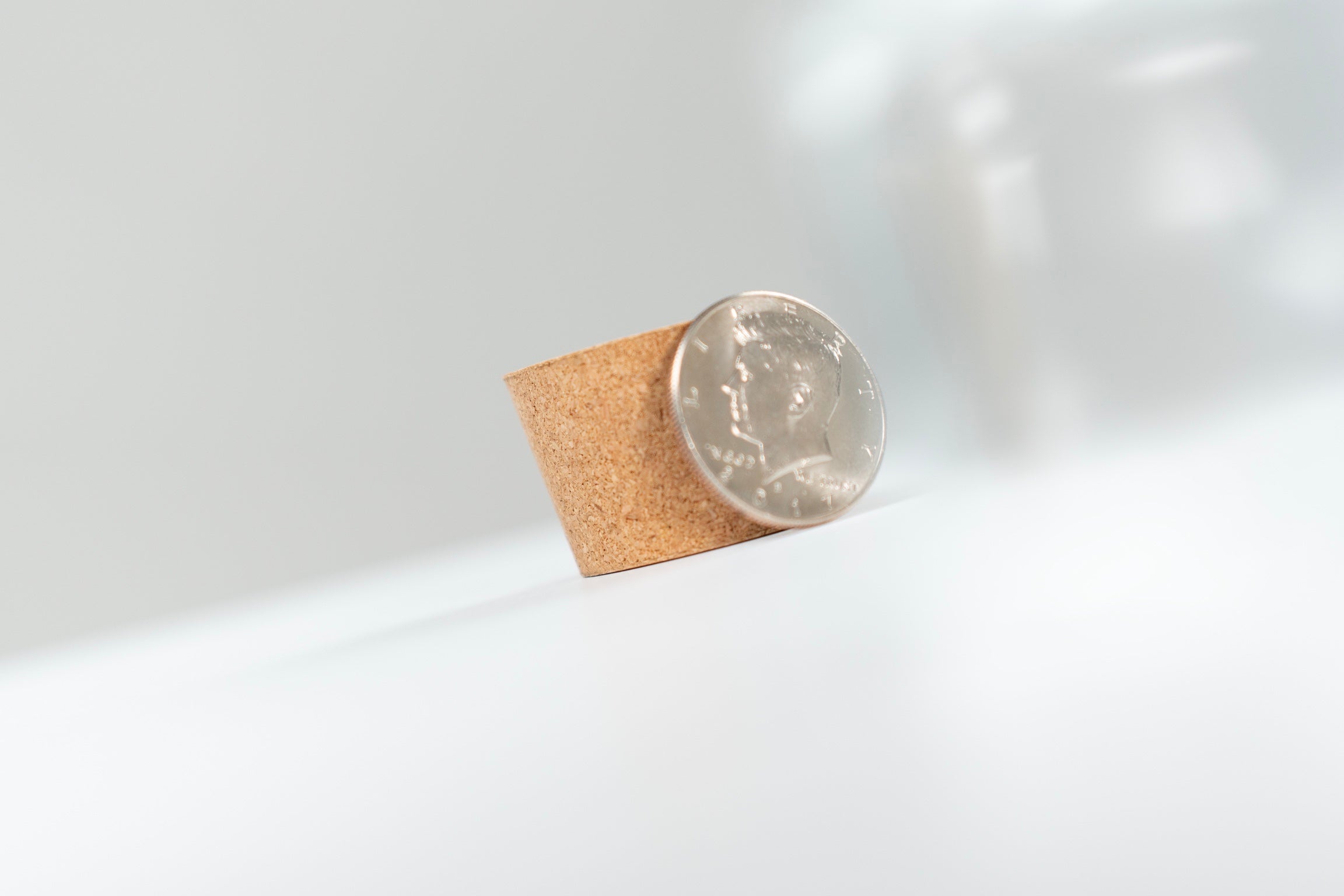 Coin standing against a small cork insert for Coin Pitcher